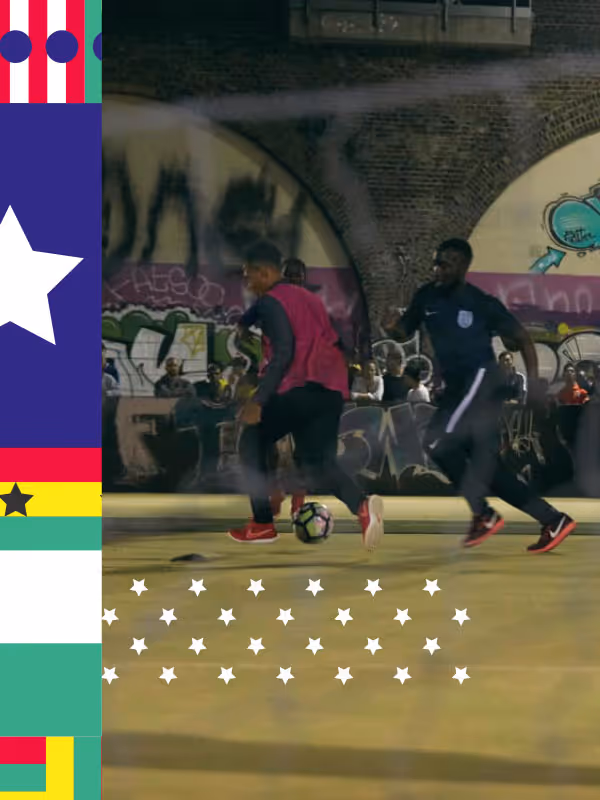 Two footballers in action on a pitch at night with graffiti in the background, bordered by a colorful striped and star-patterned frame.