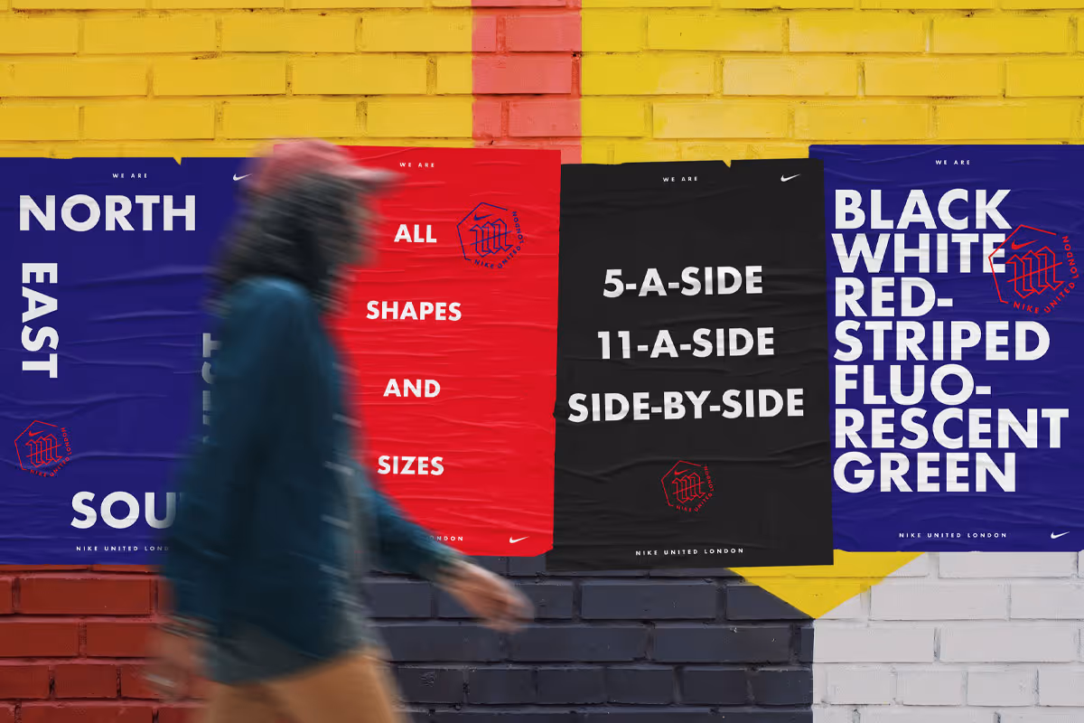 Blurry figure walking past a vibrant mural composed of four vertical banners, each with bold text. From left to right: blue with 'NORTH EAST', red with 'ALL SHAPES AND SIZES', black with '5-A-SIDE 11-A-SIDE SIDE-BY-SIDE', and blue with 'BLACK WHITE RED-STRIPED FLUORESCENT GREEN'. All banners feature the Nike United London logo.