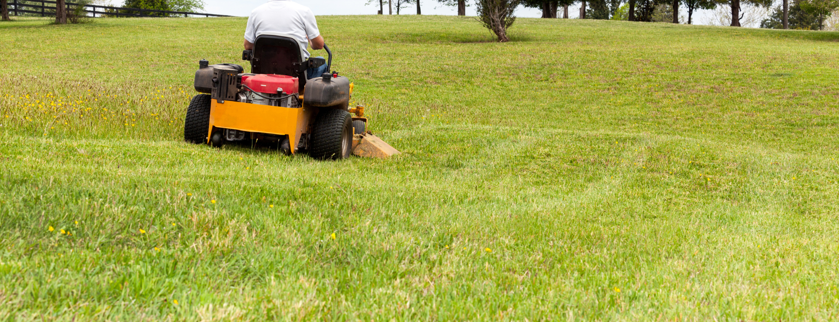 Image of a riding lawn mower cutting a green field of grass
