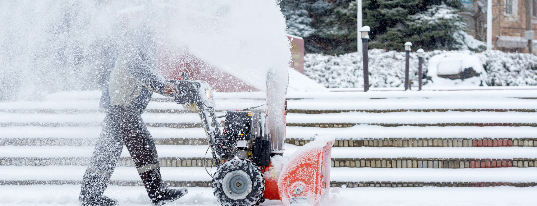 Image of a person using a snow blower to clear off a sidewalk