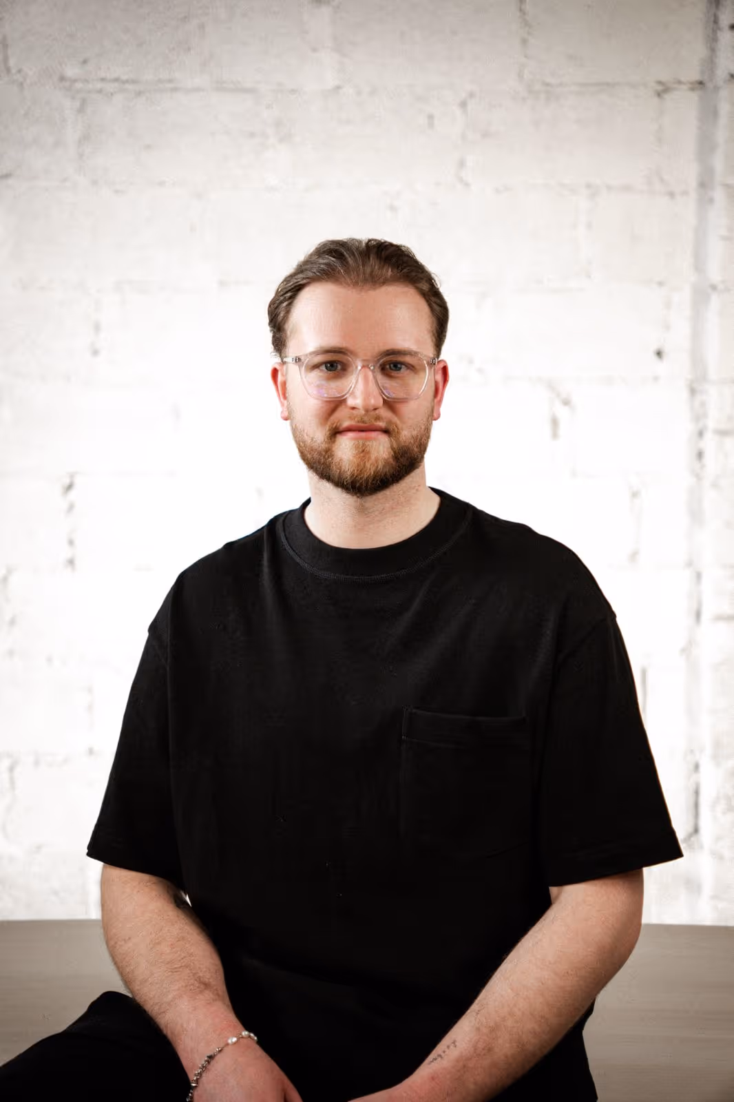Image of a man in an office space, sitting on a stool