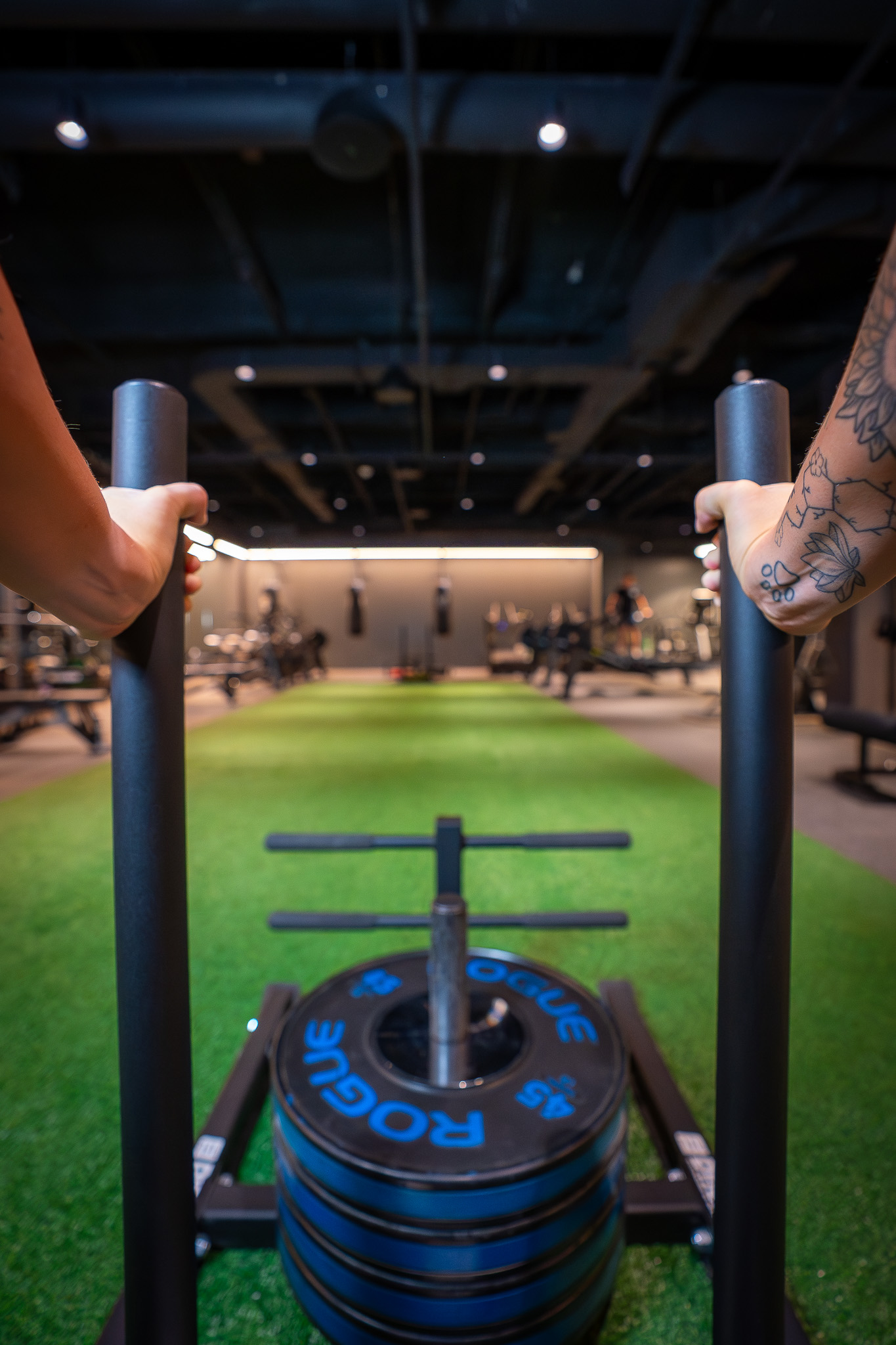 Member point of view of doing a sled push on the turf at FIELDHOUSE gym