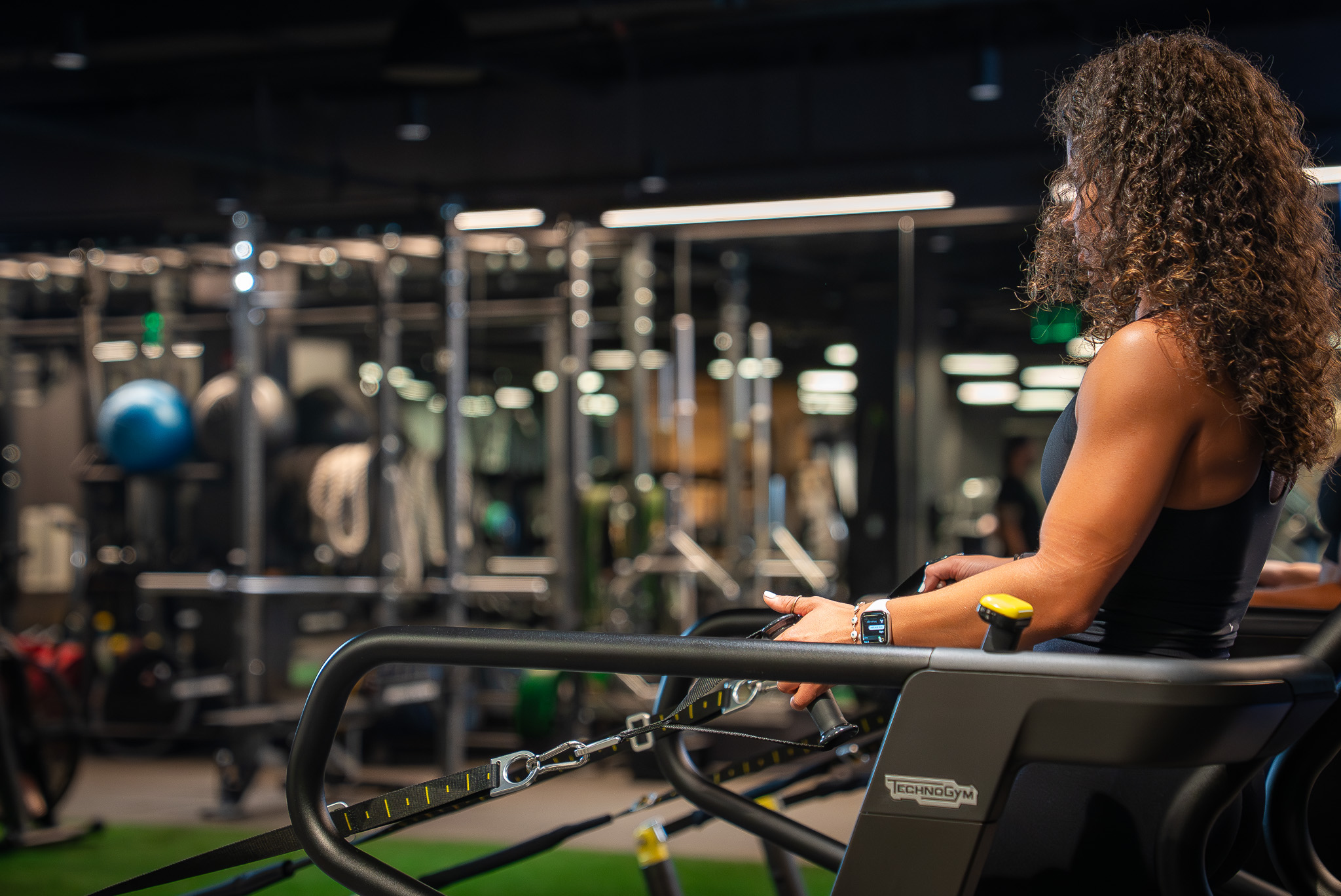 Members working out at FIELDHOUSE gym, utilizing cardio machines and strength training equipment.