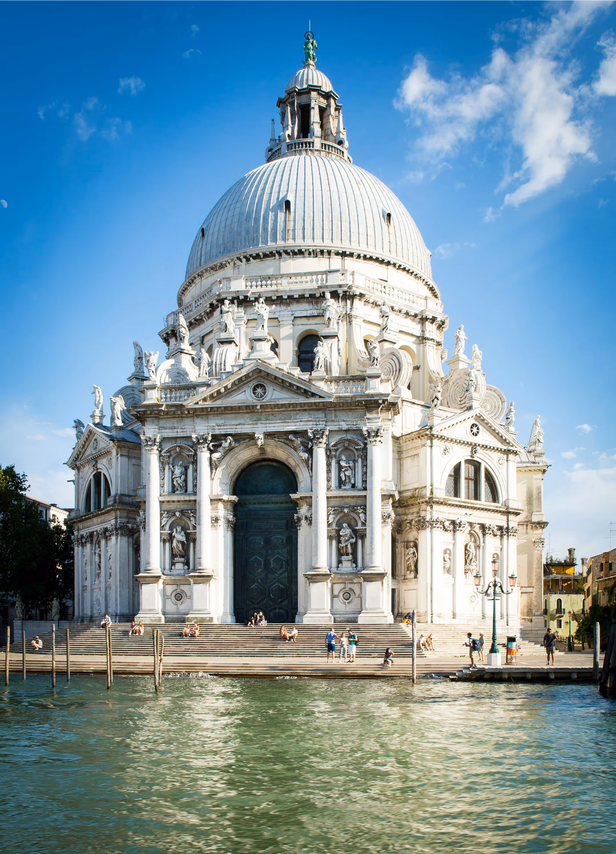Santa Maria della Salute basilica with large dome and ornate statues by a canal in Venice, Italy.