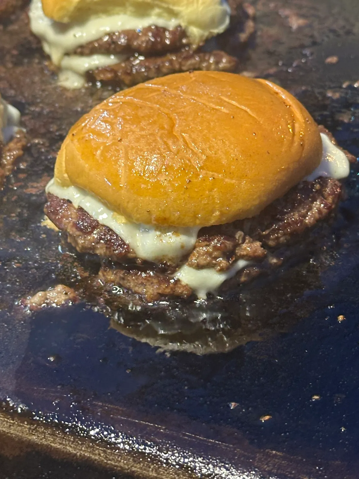 Burger Supreme steaming on the griddle with melted white American