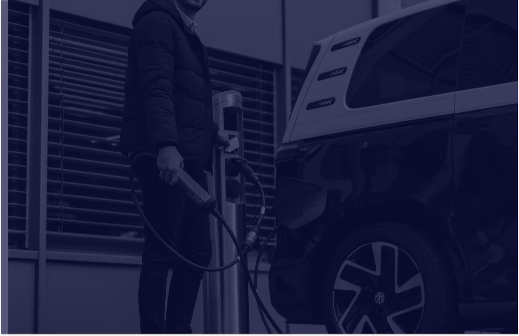 Person charging an electric Volkswagen van at a public station.