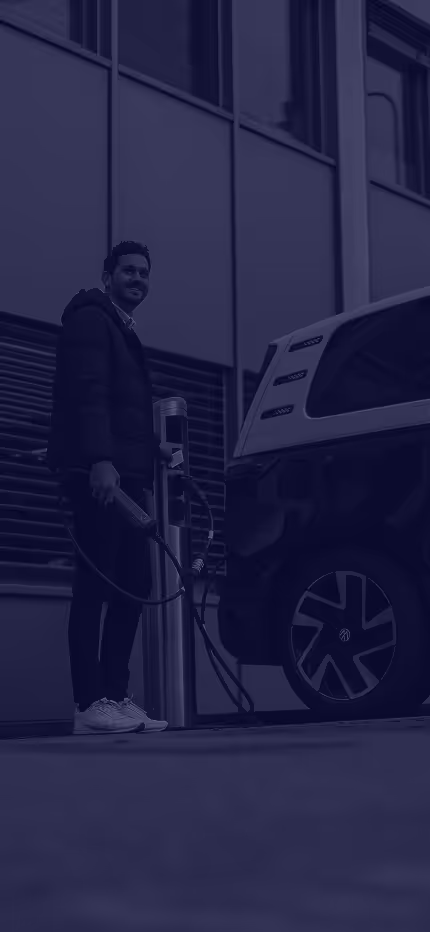 Person charging an electric Volkswagen van at a public station.