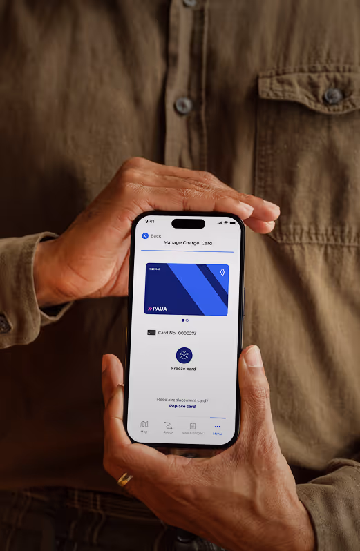 A person holds a smartphone showing the Paua app’s "Manage Charge Card" screen, prompting card details for verification.