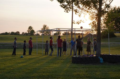 A group of youth playing ball outside on the farm.
