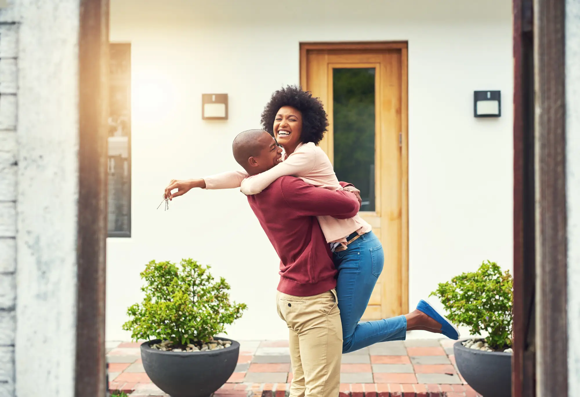 Couple embracing while woman holds keys in front on home.