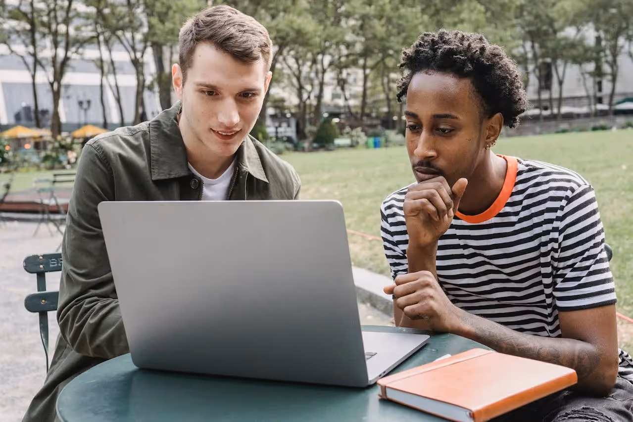 two male students discussing on laptop_ Online IT Certification Program