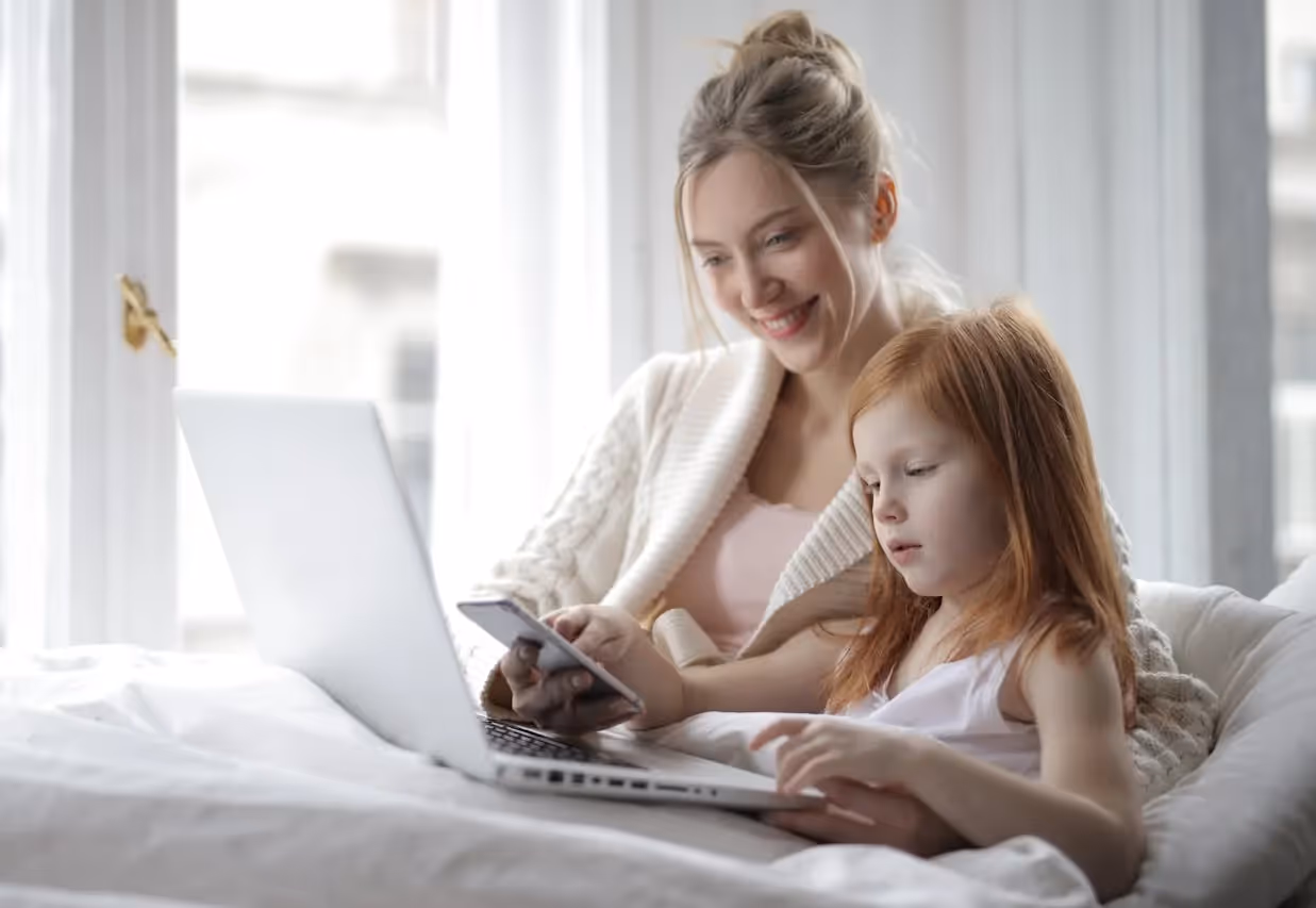 Mother studying with young children playing in background.