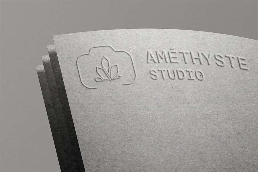 Papier gaufré avec logo d'un cristal et texte « AMÉTHYSTE STUDIO » en relief.