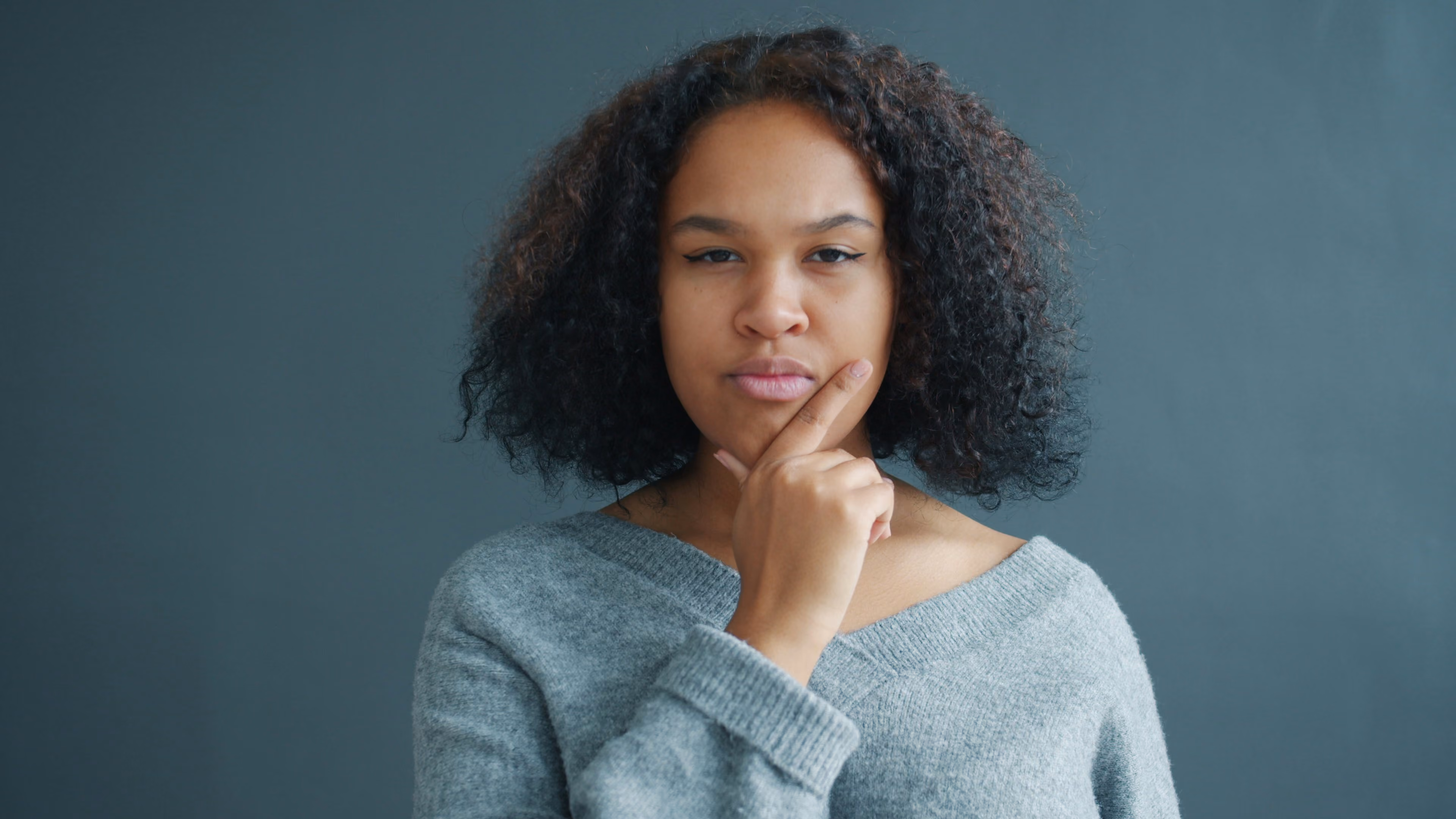 Femme pensive, la main sur le menton, qui hésite entre un site vitrine et une boutique en ligne