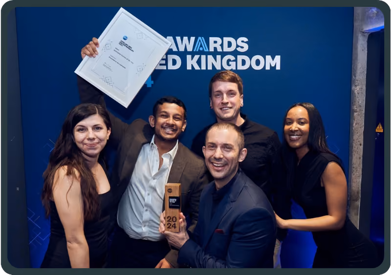 Five people smiling together, one holding a framed certificate, another holding a 2024 award trophy.