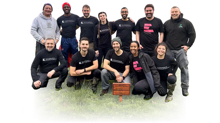 Group of eleven people outdoors posing on grass, most wearing Ecommerce Accountants shirts, smiling at camera.