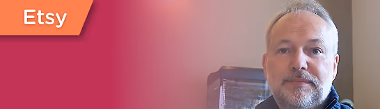 Man with short gray hair and beard looks at camera with a gradient red background and Etsy logo.