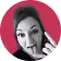 Portrait of a woman with long dark hair resting her face on her hand against a pink background.
