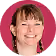 Smiling woman with light complexion and straight brown hair against a pink background.