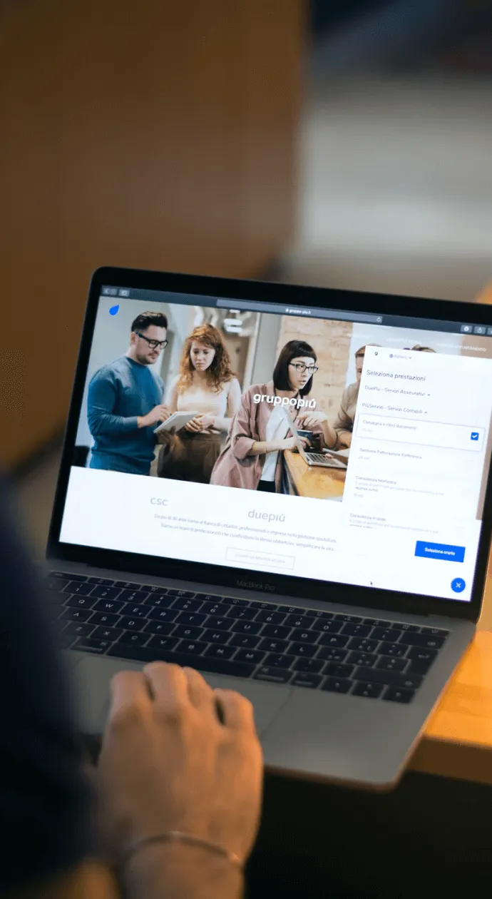 Personne utilisant un ordinateur portable MacBook Pro affichant une page web avec l'image de trois personnes collaborant autour d'une table.