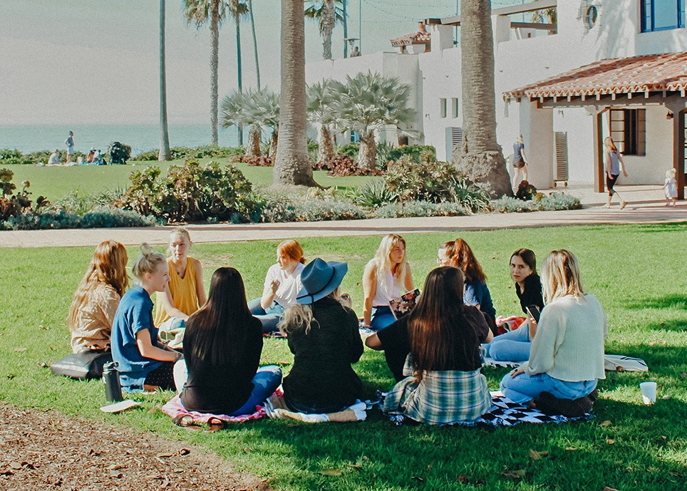 A group of people sitting in a circle on the grass. 