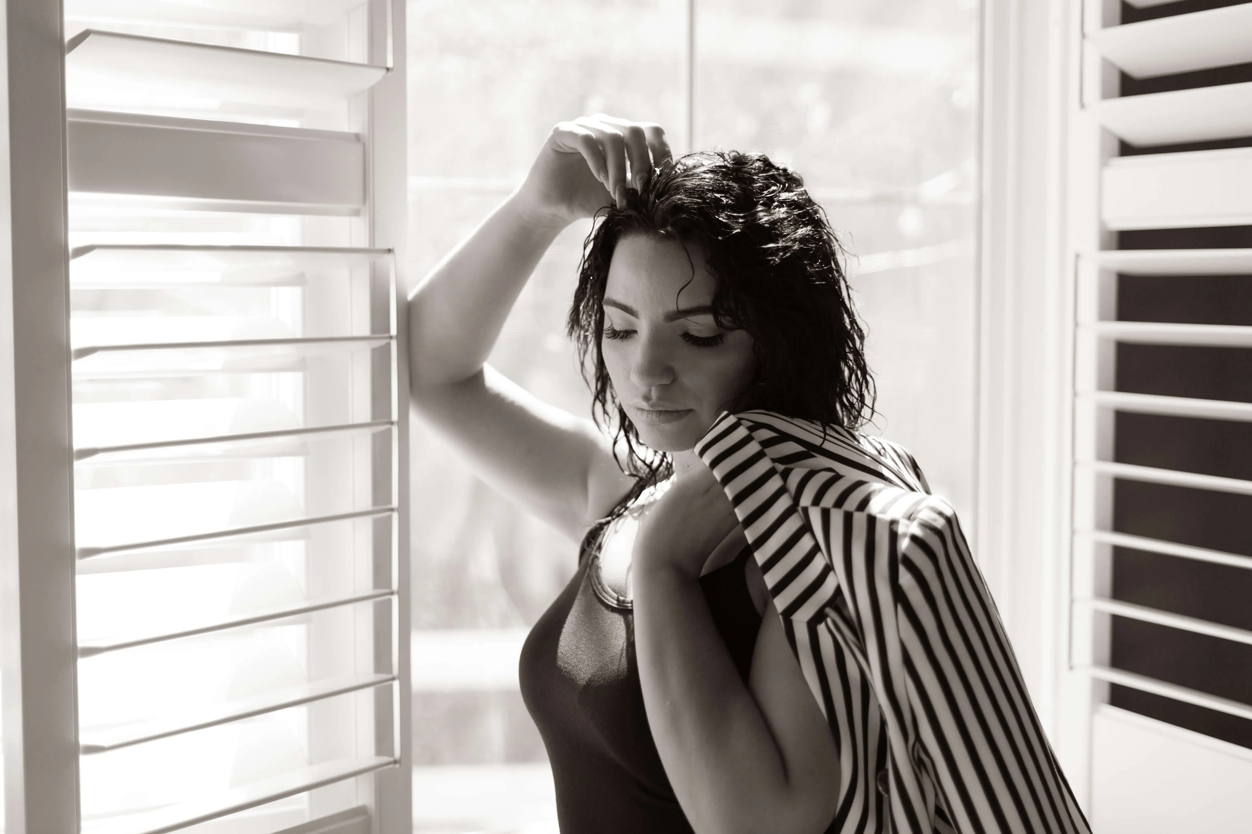 woman standing in between windows holding a coat