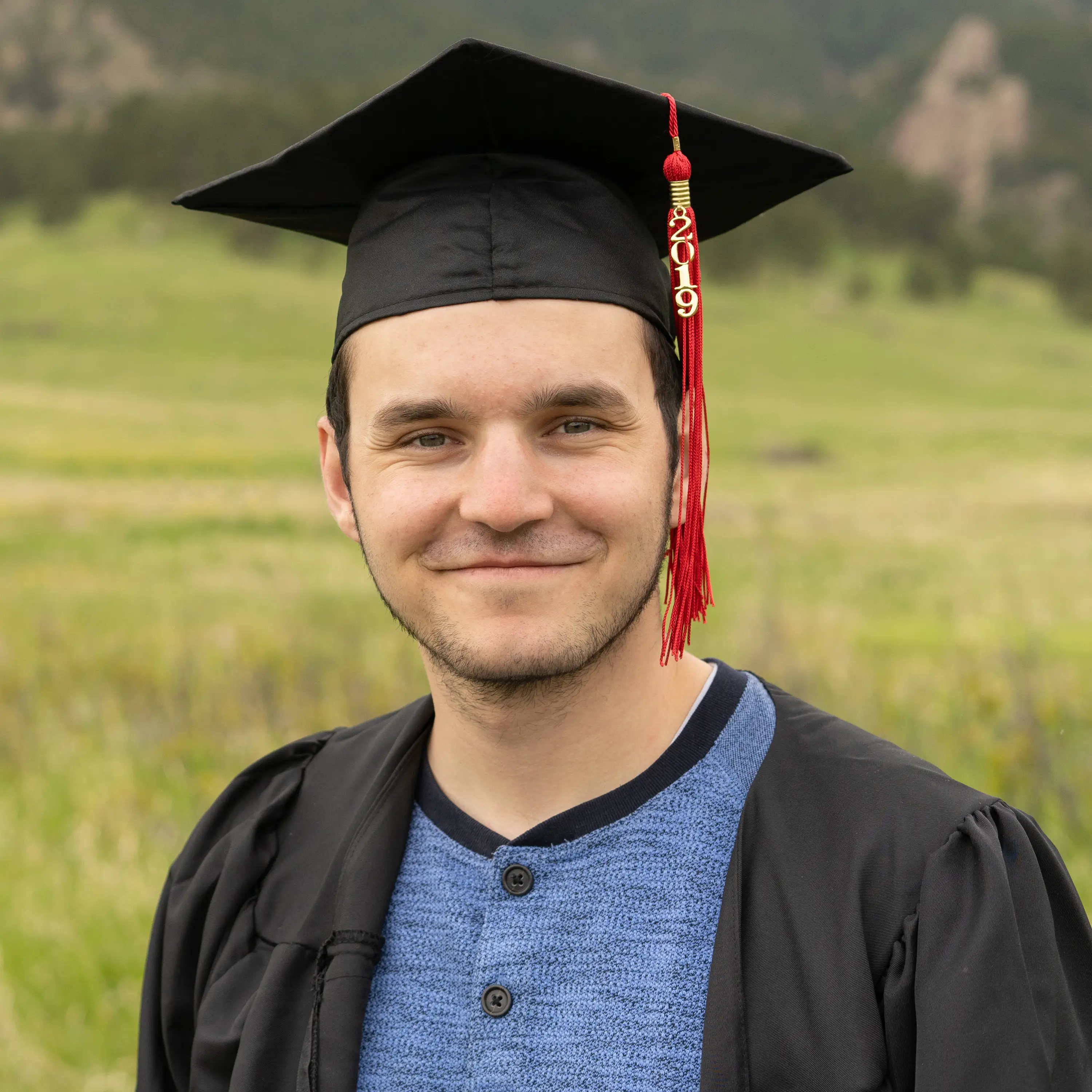 Jacob wearing a graduation cap standing in a grass field