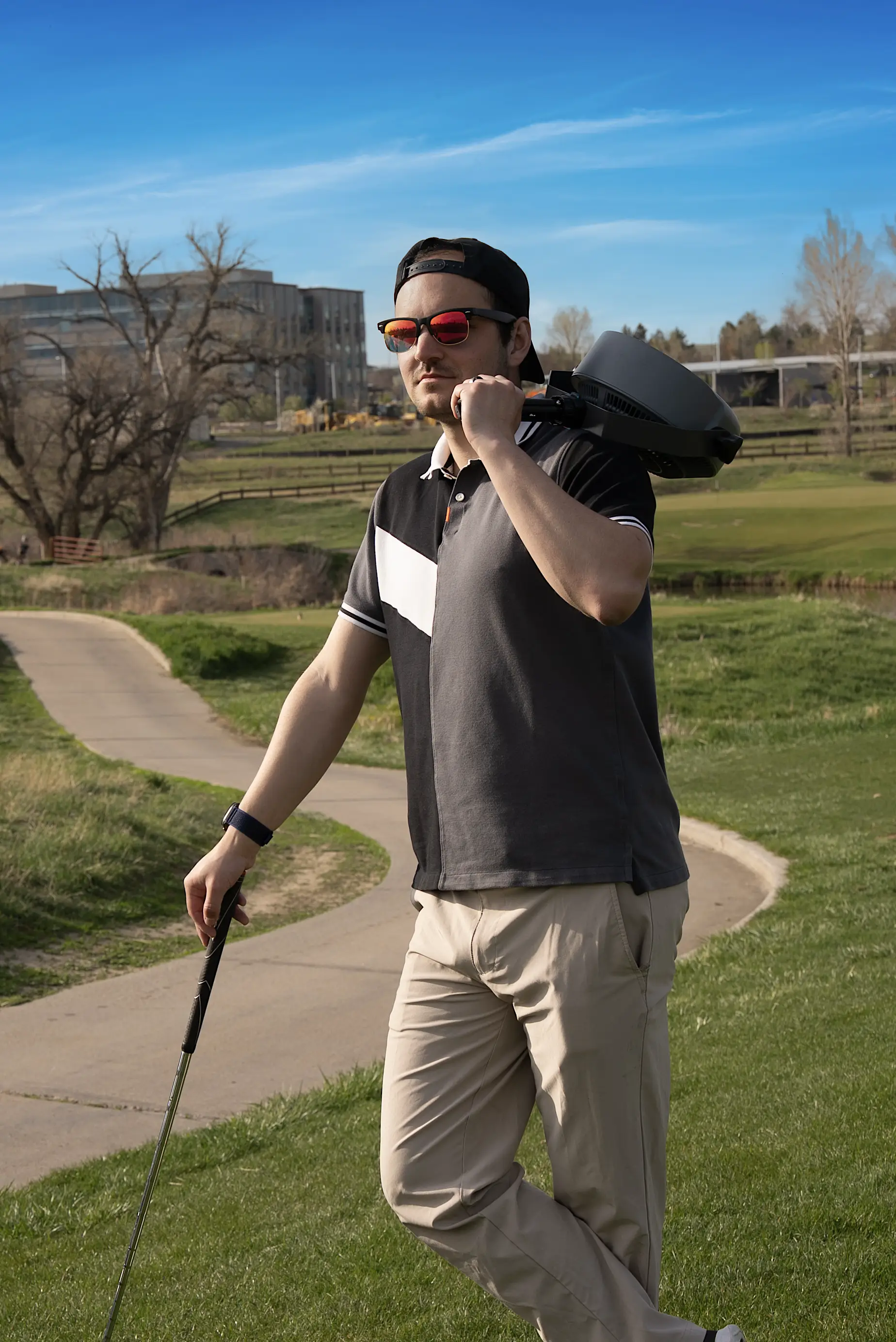 Jacob posing with a portable fan and a golf club on a golf course