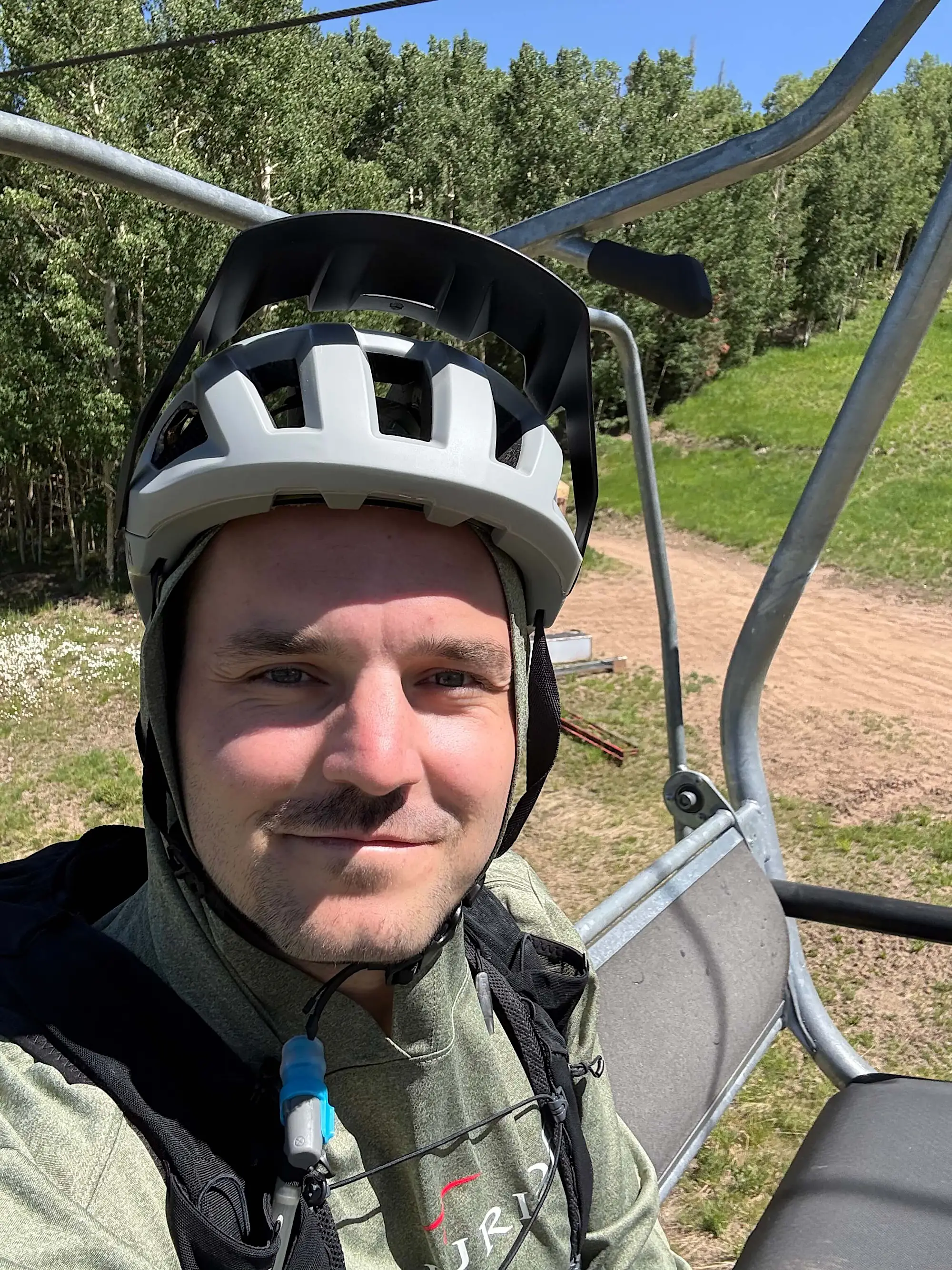 Jacob sitting on a ski lift in summer mountain biking