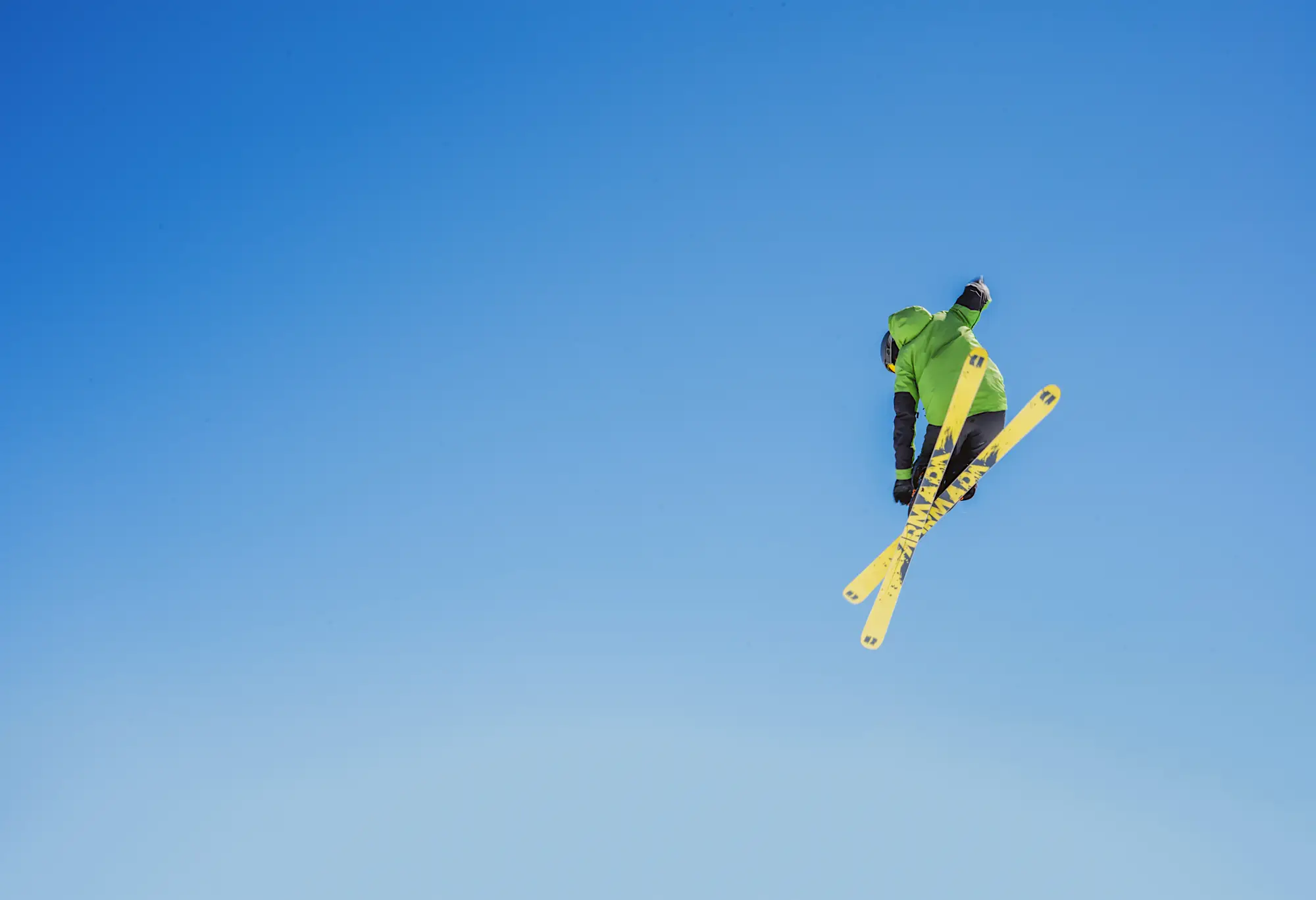 Skier appearing to fly through the air after taking a jump against a clear blue sky