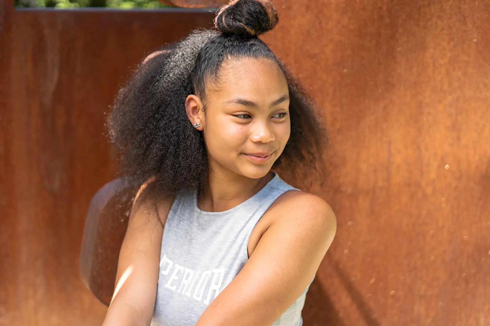 Young woman looking off to the left of the camera against an art installation piece