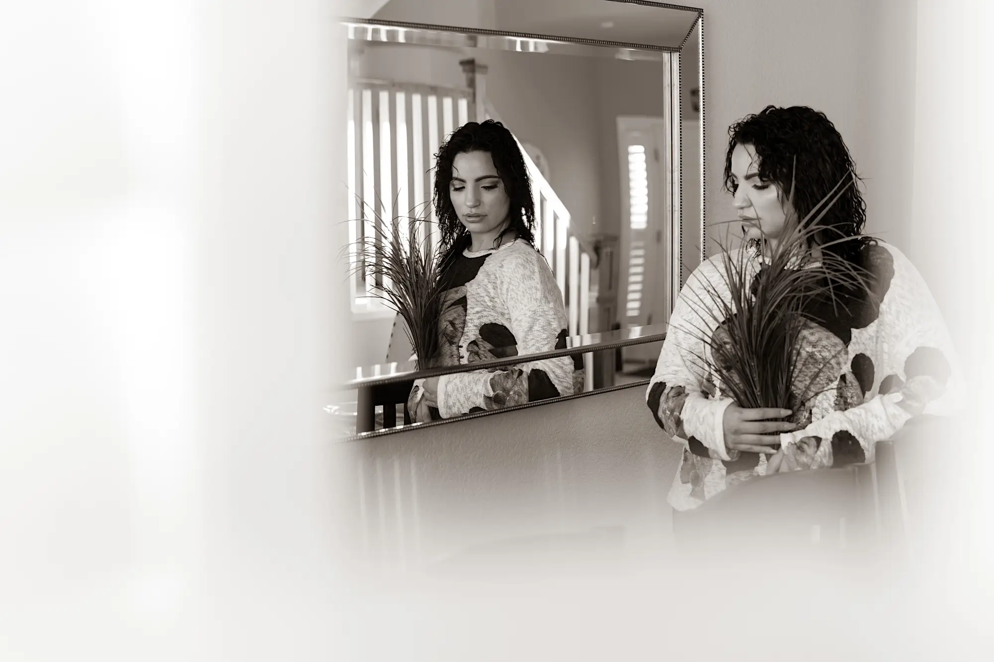 Woman staring in a mirror holding flowers