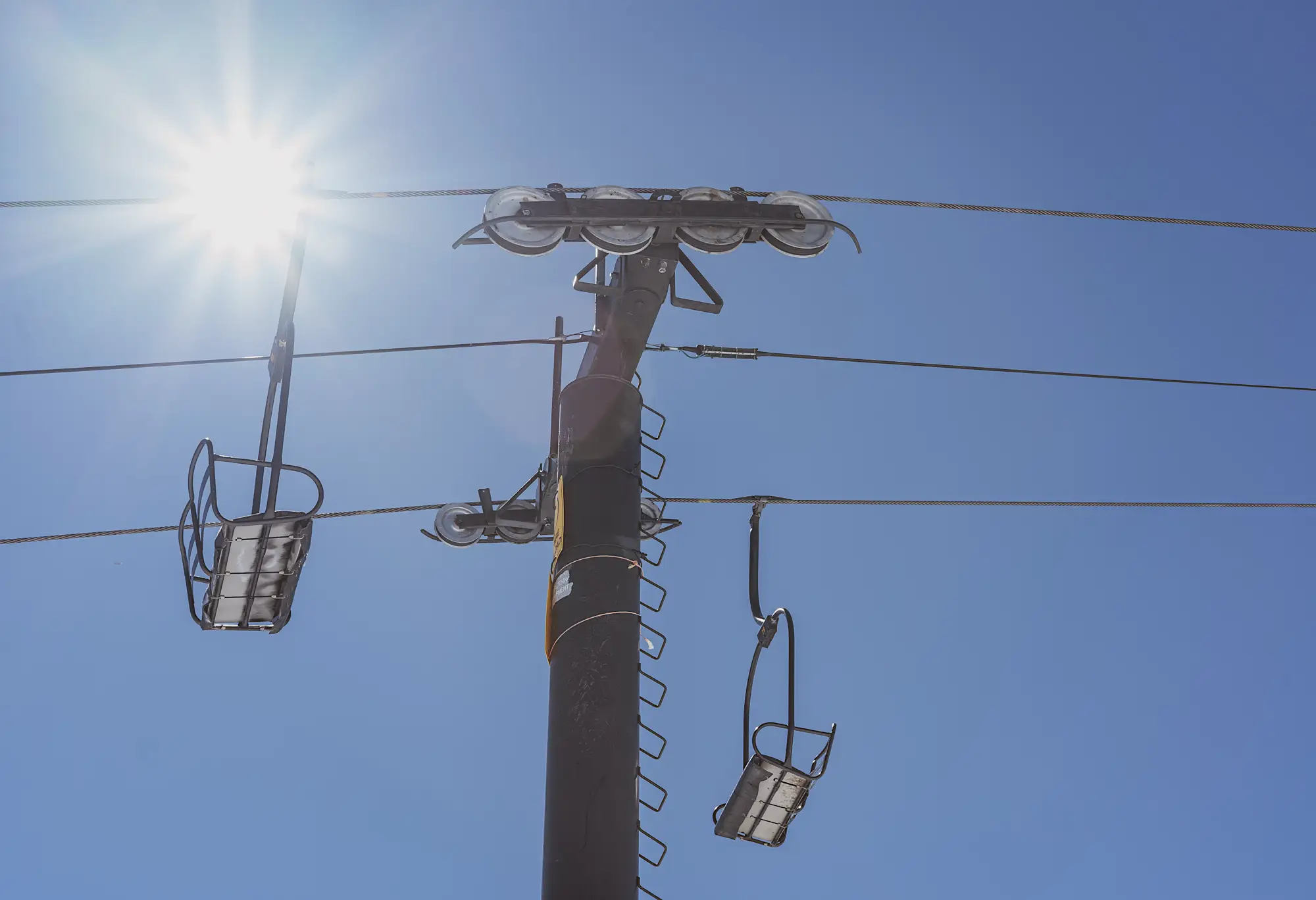 Ski lift and ski pole against a clear blue sky and shining sun