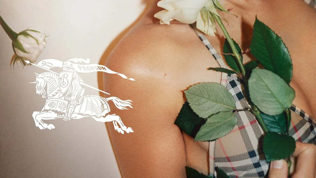 Das »Equestrian Knight«-Motiv von Burberry auf einer Nahaufnahme einer Schulter einer Frau, die eine weiße Rose hält