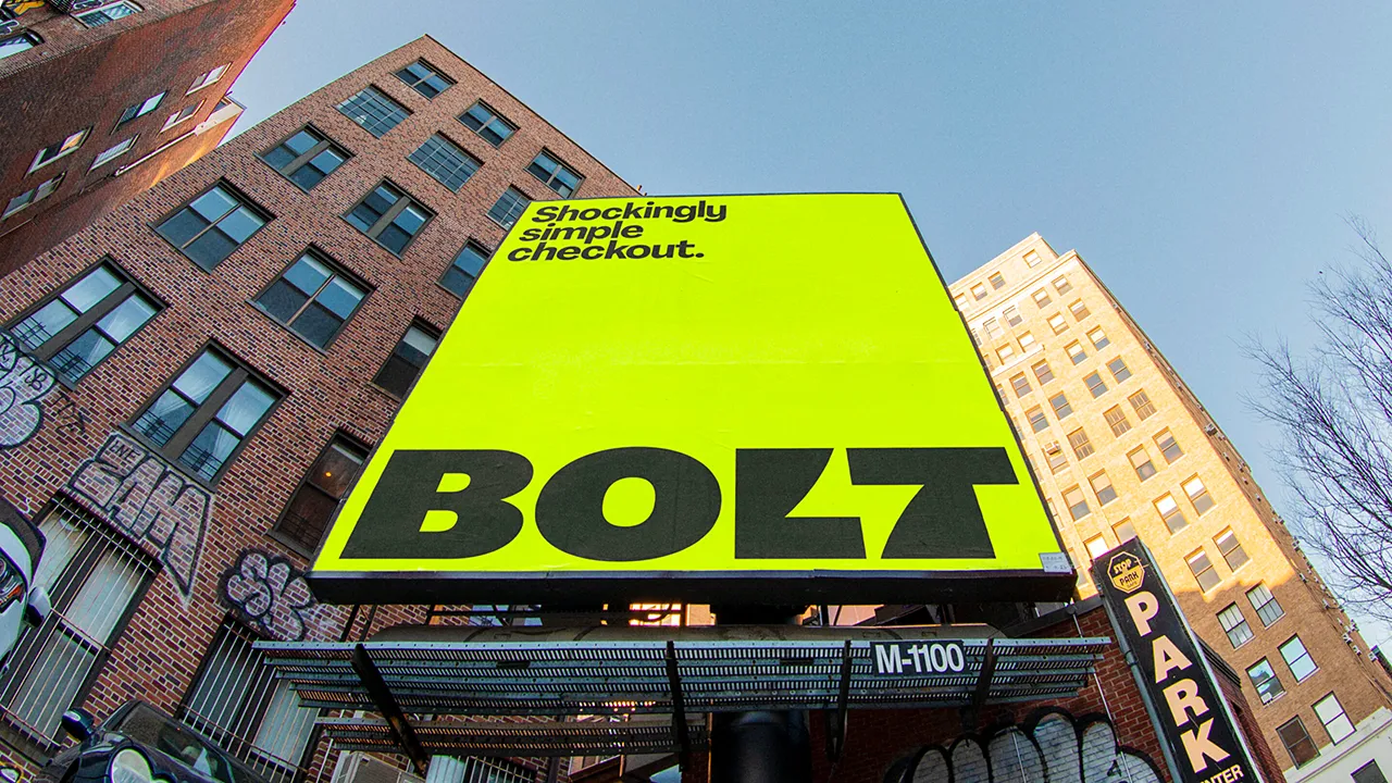 Ein riesiges neongelbes Werbeplakat der Firma Bolt vor Hochhäusern.