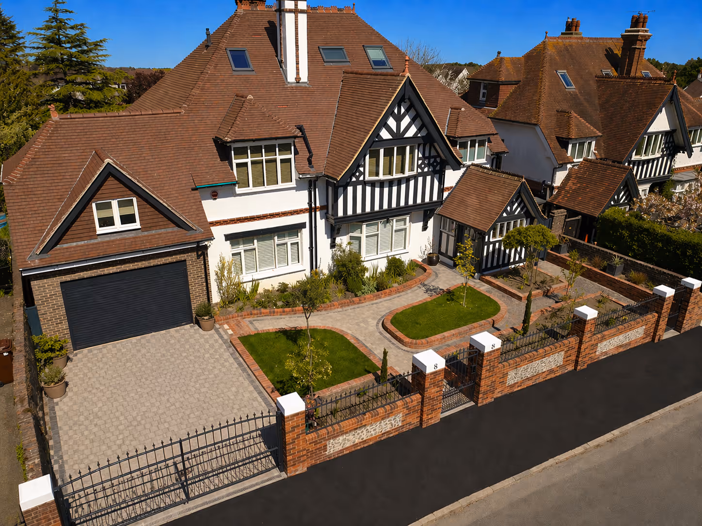 A large, two-story house with a brown roof and a well-maintained front garden.