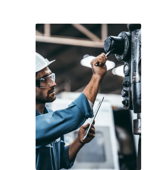 Image of maintenance worker looking at MaintainX application on a tablet device while working on equipment