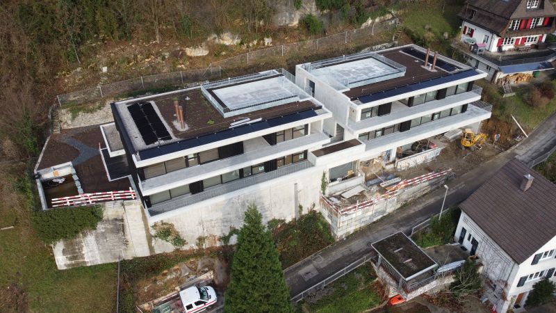 Luftaufnahme eines modernen Mehrfamilienhauses mit Photovoltaikanlage und Smart-Home-Technik