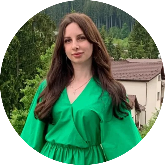 жінка в зеленій сукні стоїть перед будинком