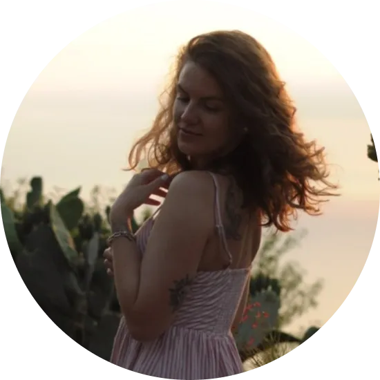 жінка в рожевій сукні стоїть серед квітів