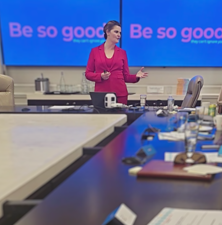 Lisa Bragg in red suit presenting in boardroom