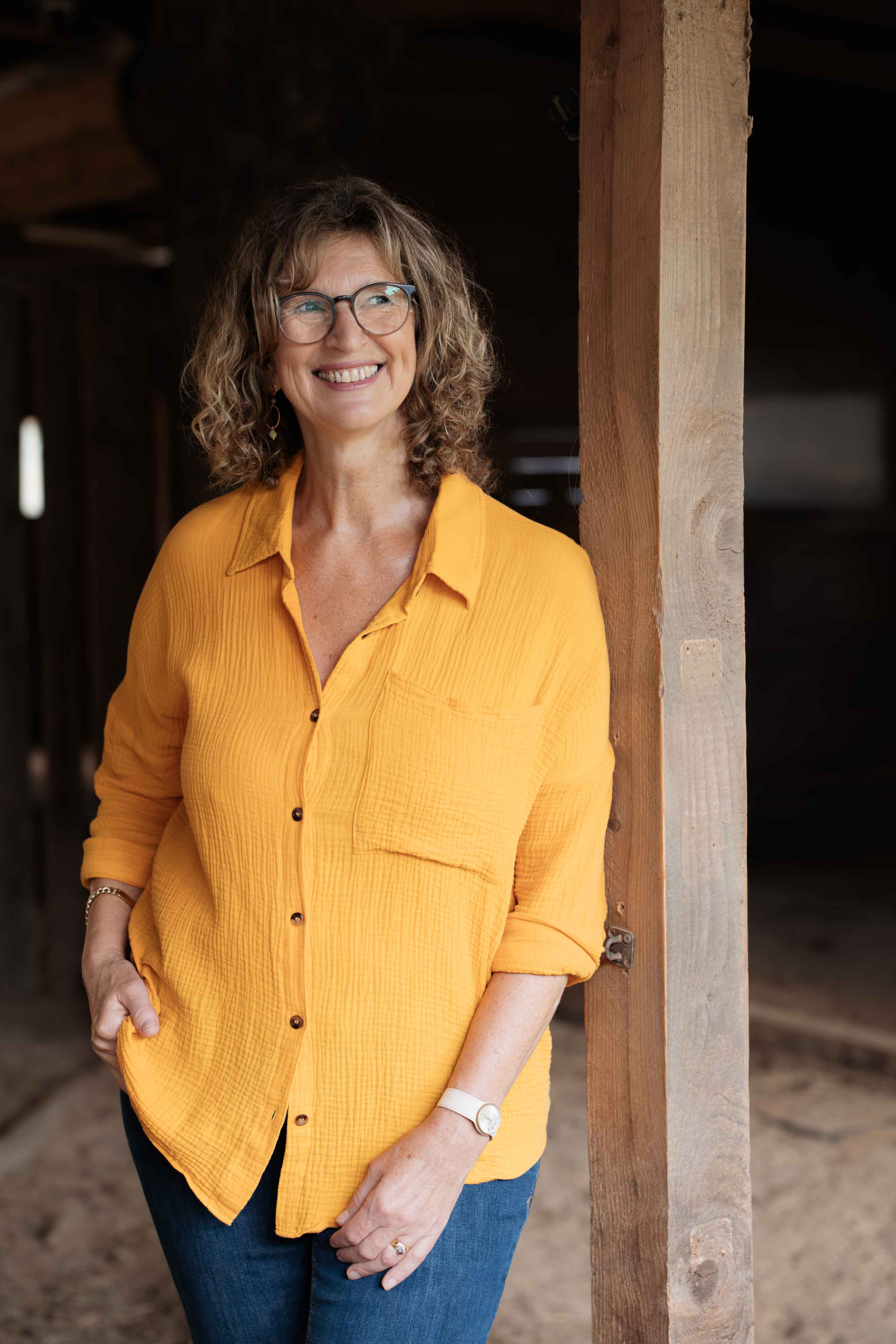 Eine Frau in gelber Bluse lehnt an einem Pfeiler.