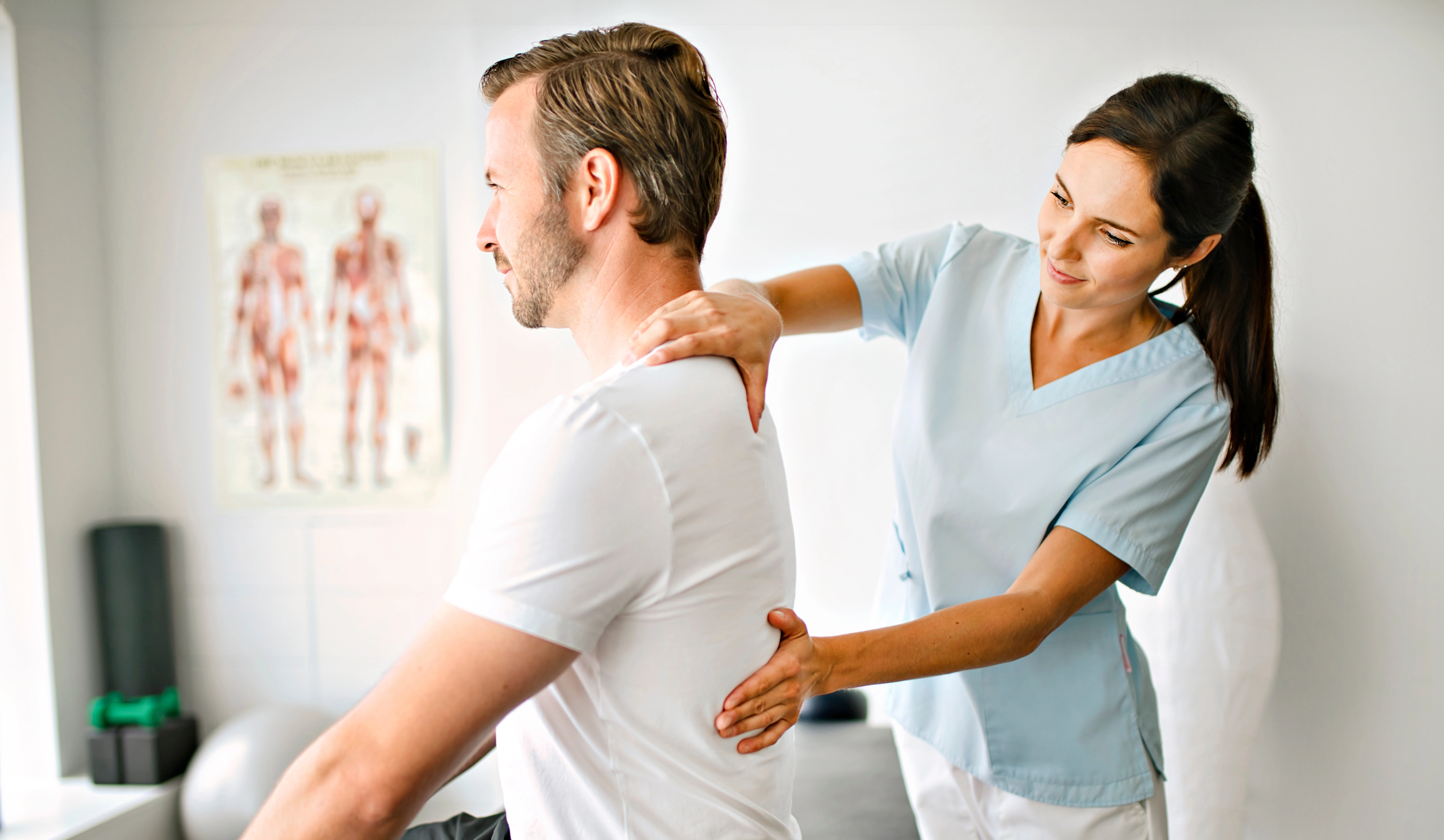 Eine Physiotherapeutin massiert den Rücken eines Mannes.