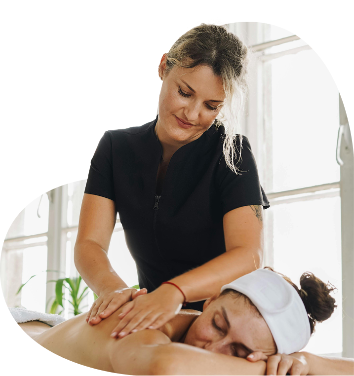 Masseurin führt entspannende Rückenmassage bei einer liegenden Frau durch – Symbolbild für Leistungen des Gesundheitsschutzes

