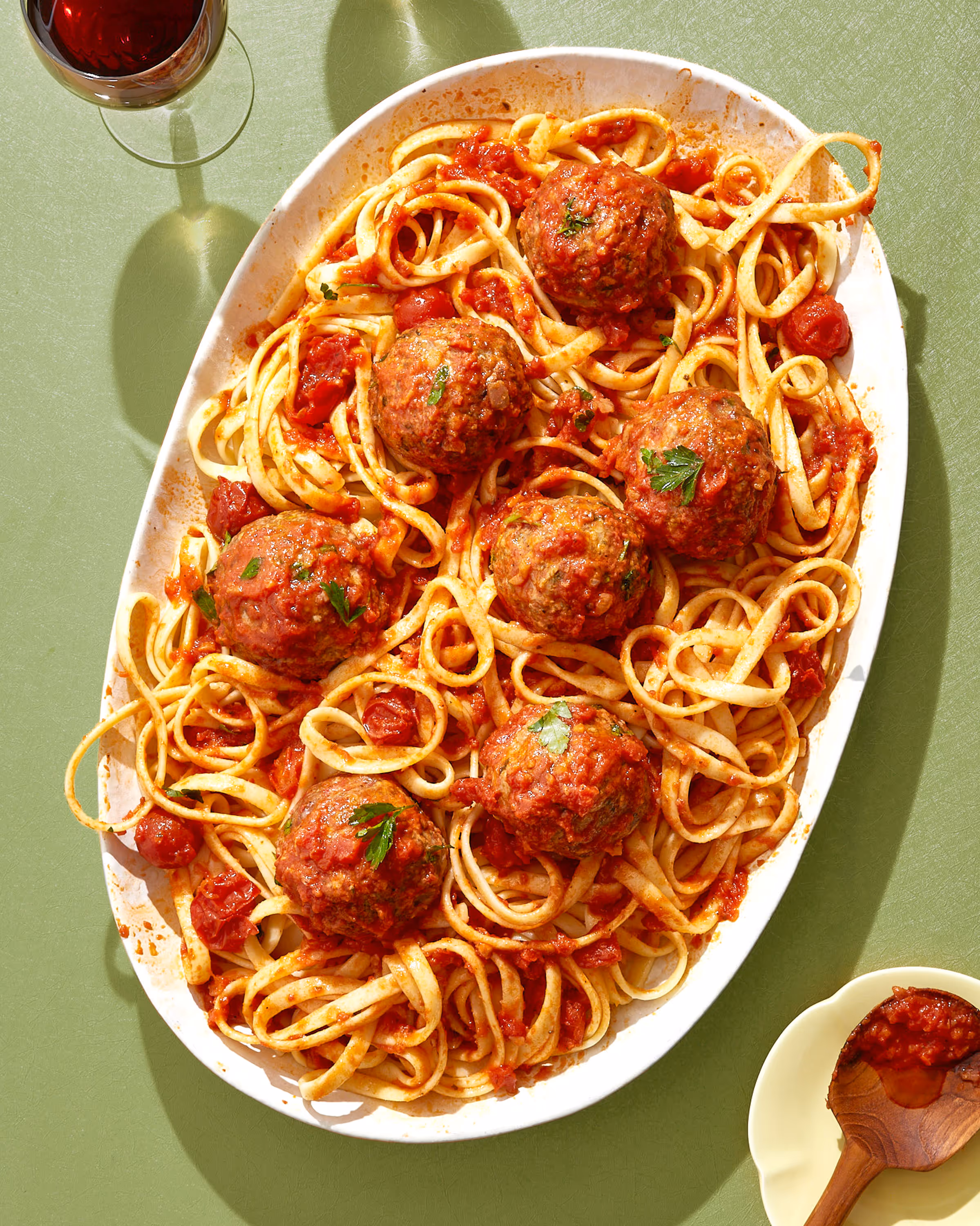 A high key overhead photo of spaghetti and meatballs on a green surface. Photo by Amy Stallard.