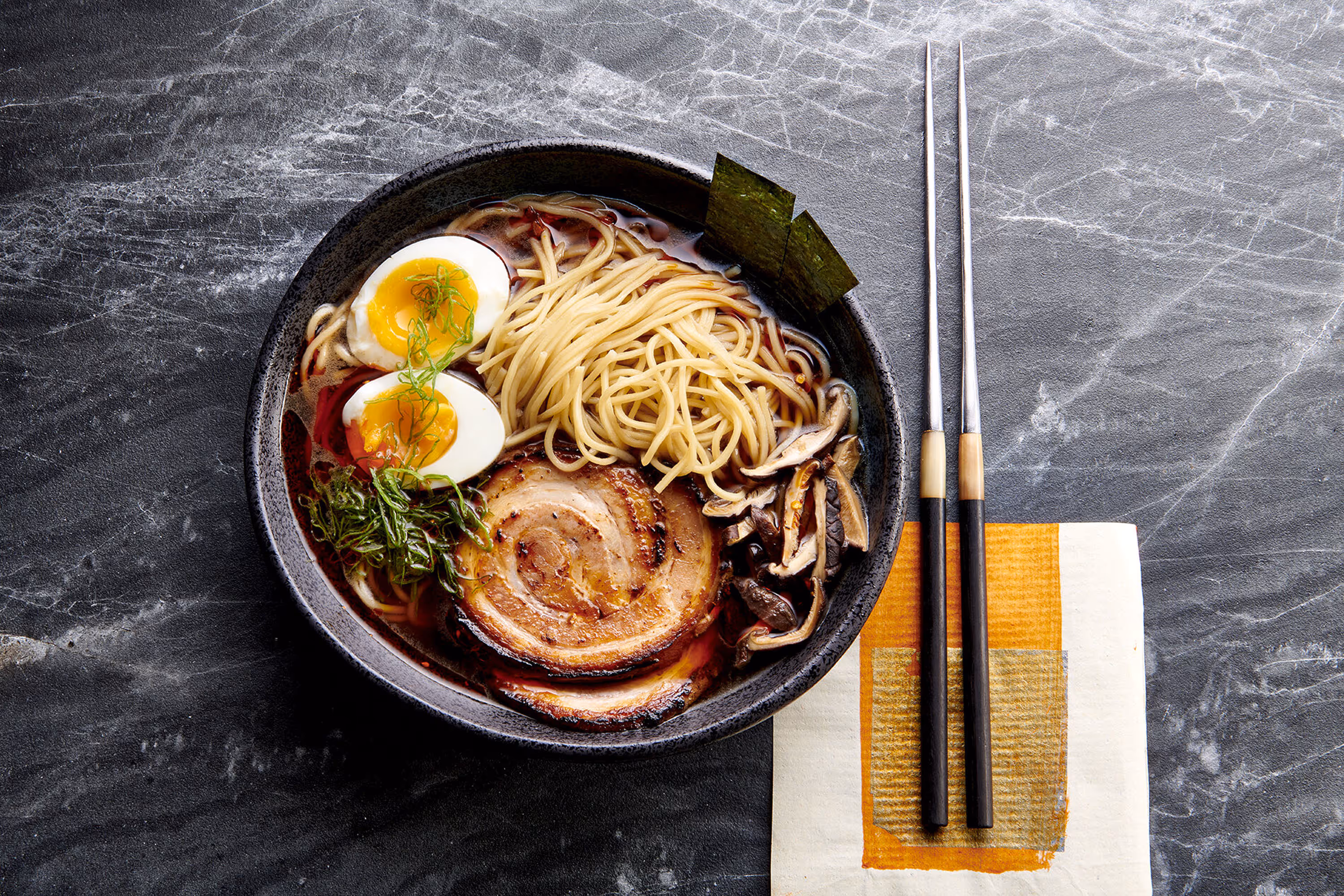 A photograph of a Savory Bibimbap soup with fancy chop sticks on a marbled surface. Photo by Ralph Smith.