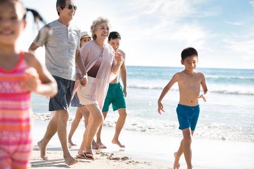 Familia china feliz corriendo en la playa
