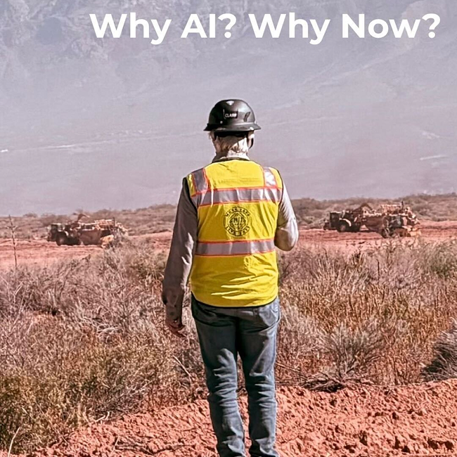 Construction worker in a yellow safety vest and hard hat standing on a desert job site, facing large equipment and distant mountains, with the text “Why AI? Why Now?” symbolizing the intersection of technology, industry, and the next era of innovation.