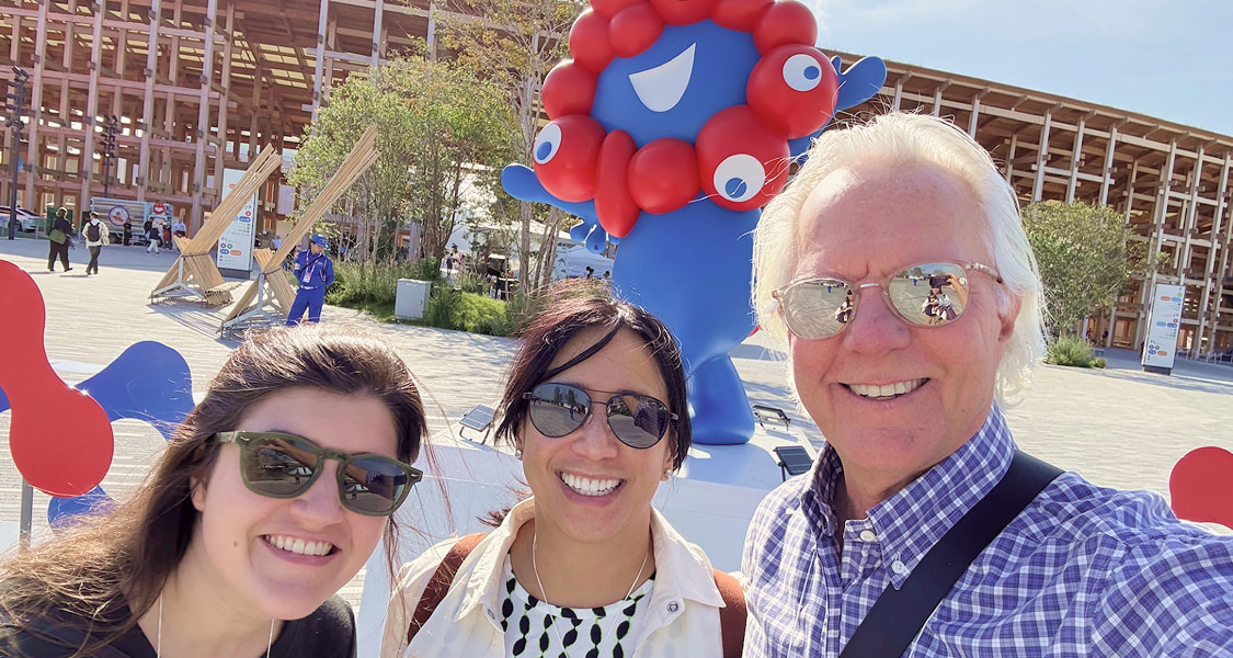 Bob Clark standing on a train platform in Japan beneath a departure sign for Shin-Osaka and Hakata, wearing sunglasses and a navy jacket.
