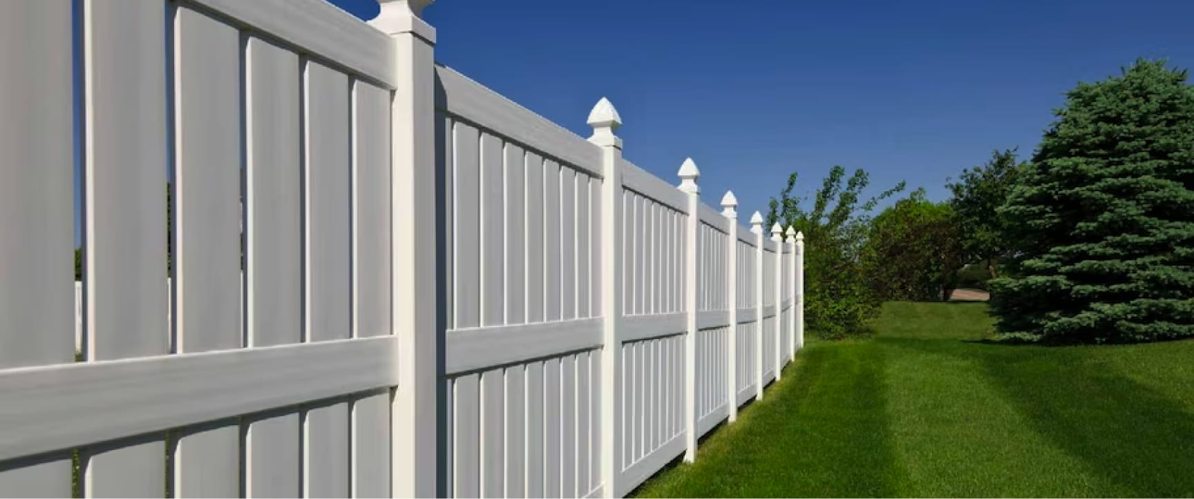A garden with high quality white wooden fences.